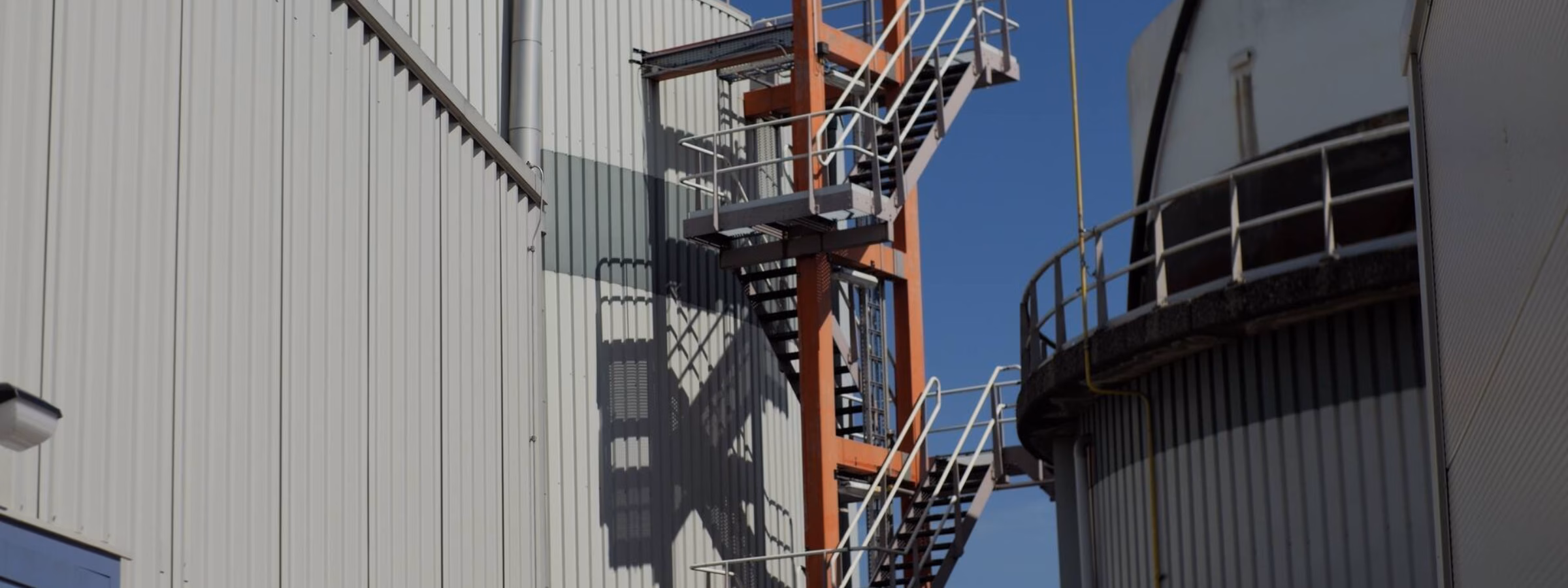 Échelle industrielle fixe et structure de plate-forme sur un site industriel, permettant l'accès aux installations en hauteur.