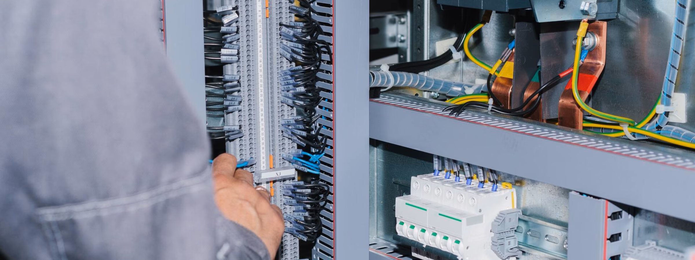 Technicus voert inspectie- of onderhoudswerkzaamheden uit aan een geopende elektrische schakelkast.