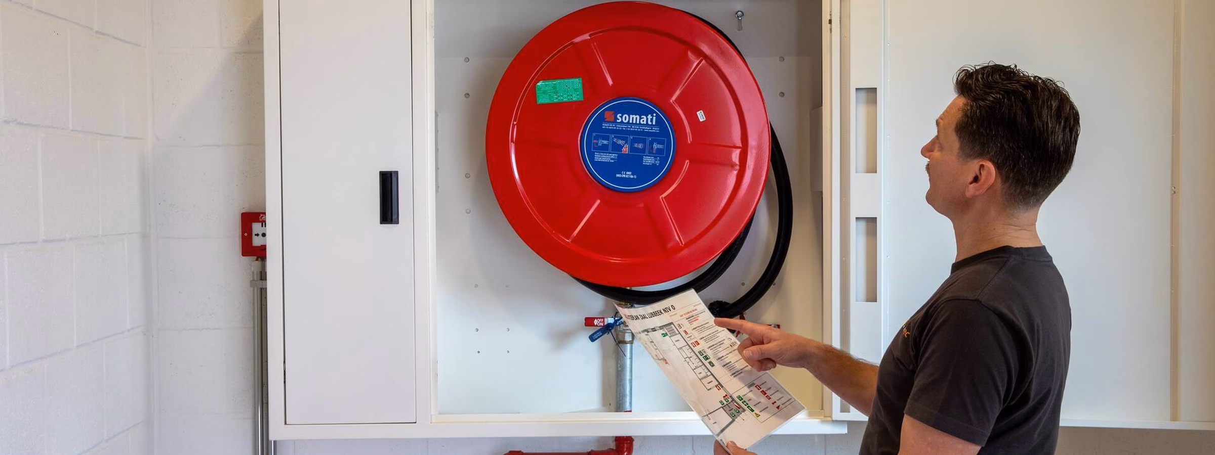 Inspection of a fire hose reel during a fire safety inspection in a building.