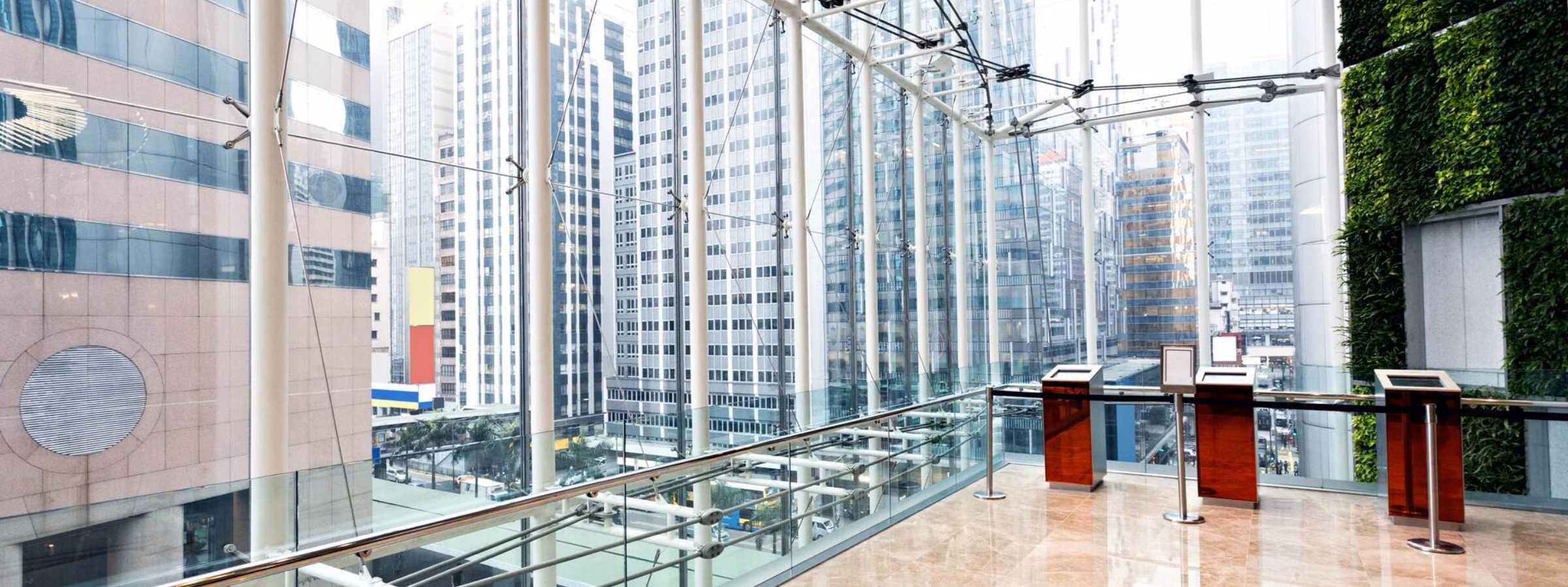 Moderne, verglaste Büro-Lobby mit Blick auf Hochhäuser und viel Tageslicht.