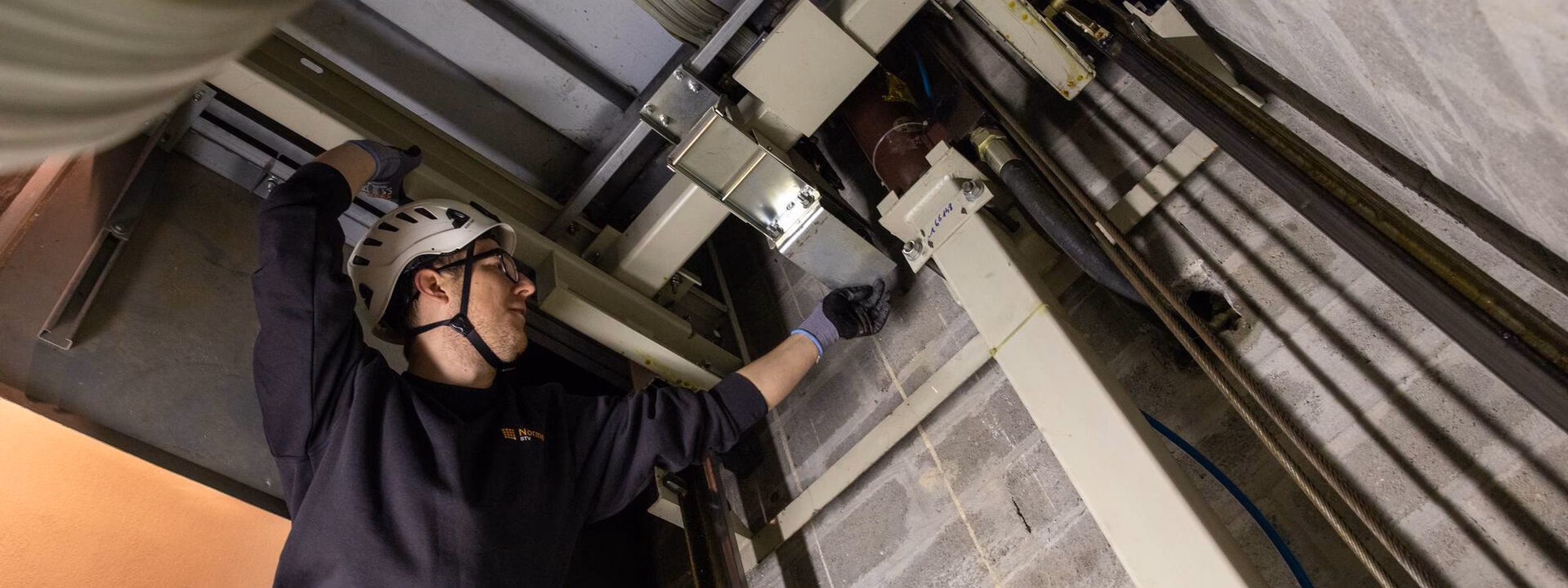 Monteur voert onderhoud uit aan een industriële deur- of liftsysteeminstallatie in een technische ruimte.