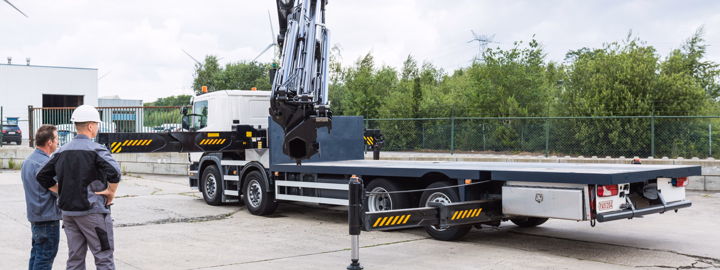 Een vrachtwagen met autolaadkraan wordt gecontroleerd tijdens een inspectie op een bedrijfsterrein.