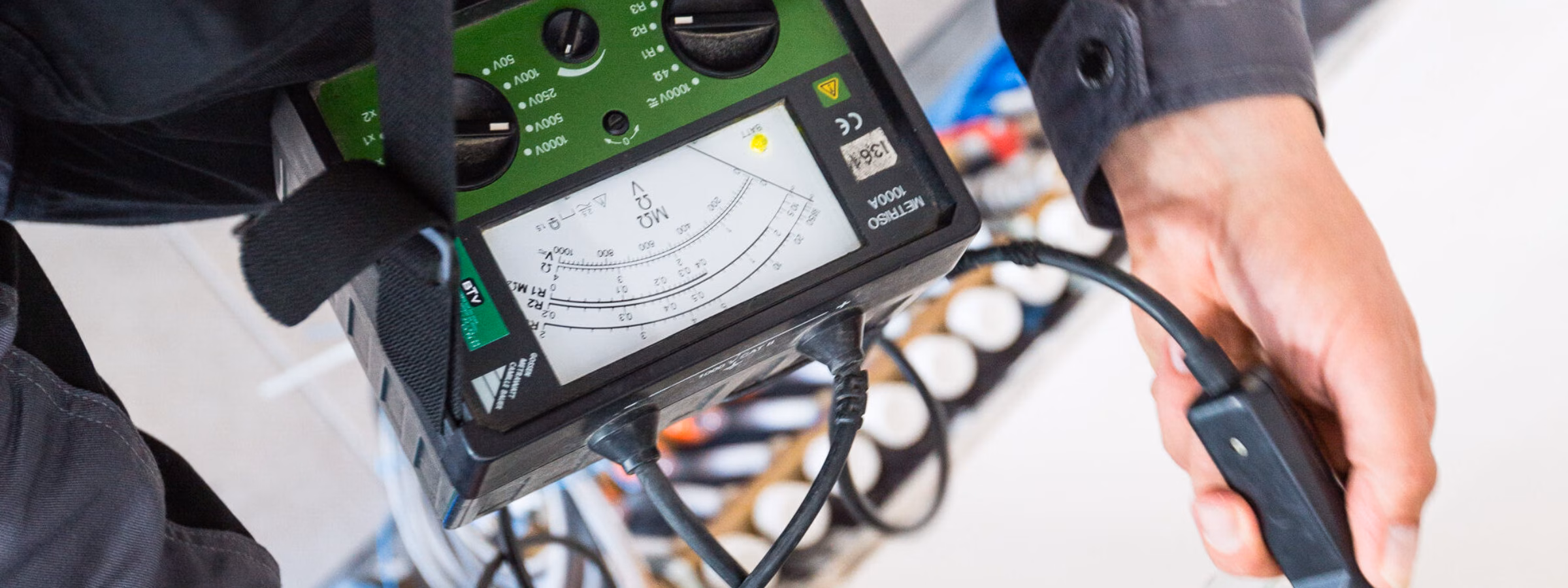 A technician is taking measurements on an electrical system for inspection and testing.