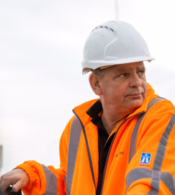 Un employé en tenue de sécurité effectue une inspection sur un site industriel.