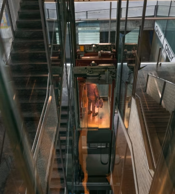 Monteur voert inspectie- of onderhoudswerkzaamheden uit aan een liftinstallatie in een technische ruimte.