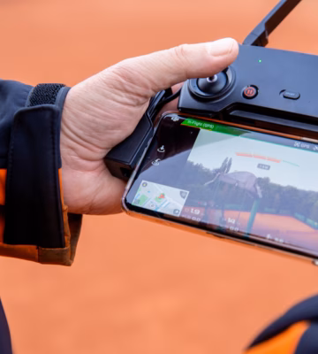 Une personne utilise une télécommande de drone couplée à un smartphone pour effectuer un vol d'inspection ou une inspection du terrain.