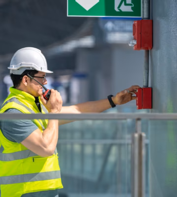 An employee tests a manual fire alarm as part of a fire alarm system in a building.