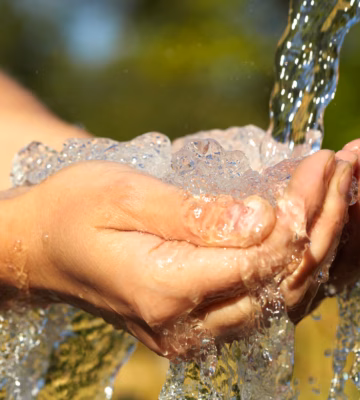 Handen vangen stromend water voor analyse van waterkwaliteit en milieuonderzoek.
