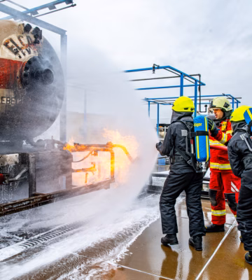 Emergency responders are fighting a fire with foam and water during an incident at an outdoor site.