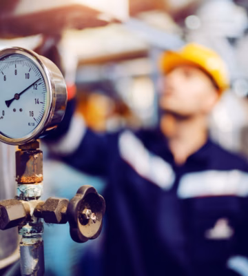 Een drukmeter wordt gecontroleerd binnen een industriële installatie.