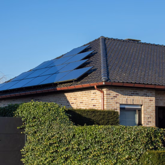 Haus mit Solarmodulen auf einem schrägen Ziegeldach in einem modernen Wohngebiet.