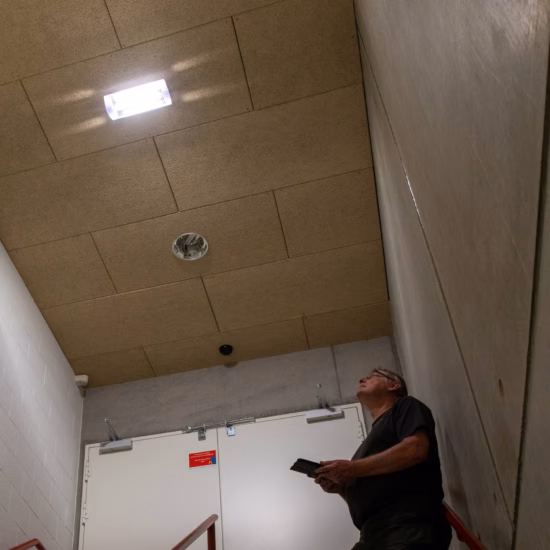 Inspecteur controleert een trappenhuis en vluchtweg met behulp van een tablet tijdens een veiligheidsinspectie.