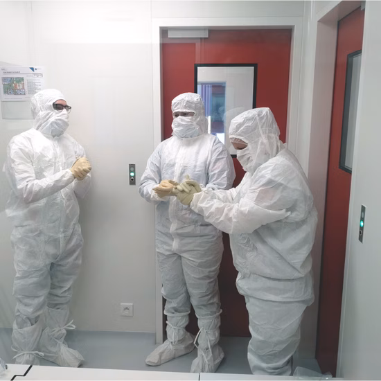 Medewerkers in beschermende cleanroomkleding overleggen in een gecontroleerde productieomgeving.