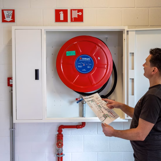 Inspection of a fire hose reel during a fire safety inspection in a building.