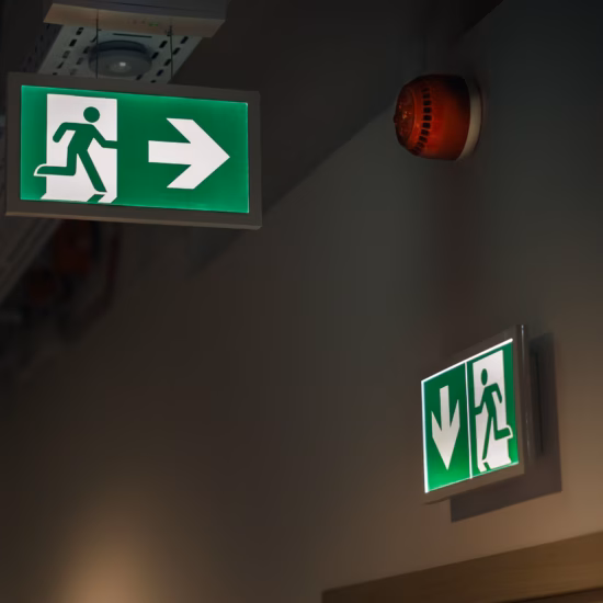 Nooduitgang met veiligheidsbordjes die de vluchtroute duidelijk aangeven voor een veilige evacuatie bij een noodsituatie.