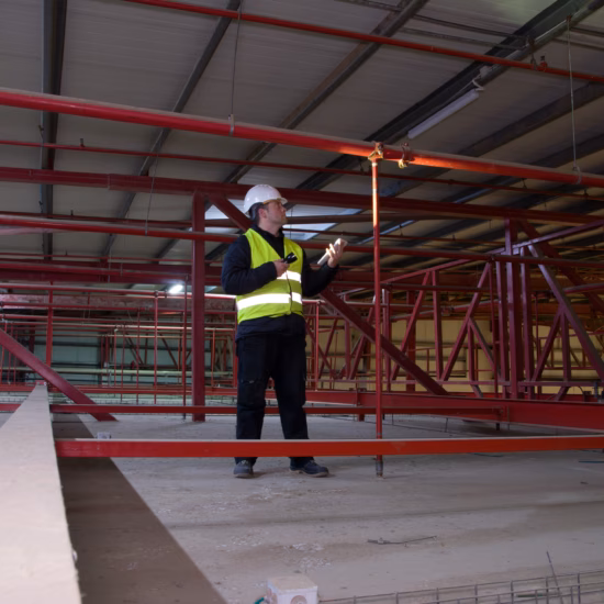 Technician engineer in a helmet checks the sprinklers pipes and roof constractions with a tablet