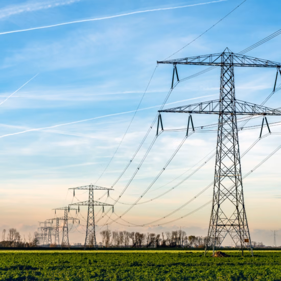 Hochspannungsmasten und Stromleitungen in einer offenen Landschaft für den Stromtransport.