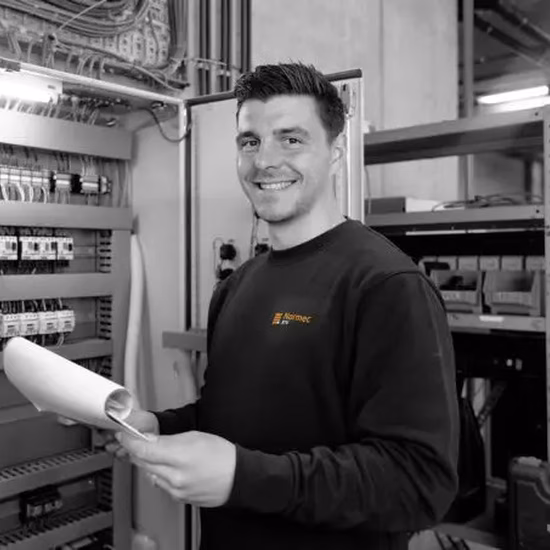 Een medewerker inspecteert elektrische componenten in een technische installatie.