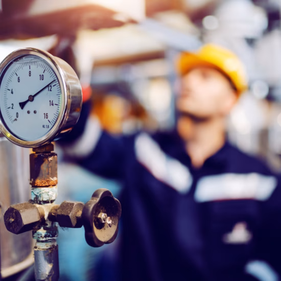 A pressure gauge is being checked inside an industrial facility.