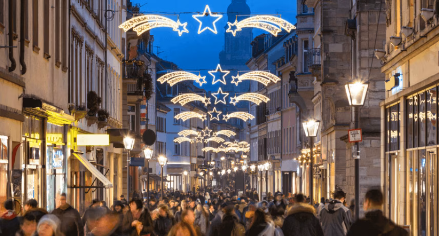 Een drukke winkelstraat is verlicht met decoratieve feestverlichting boven het publiek.