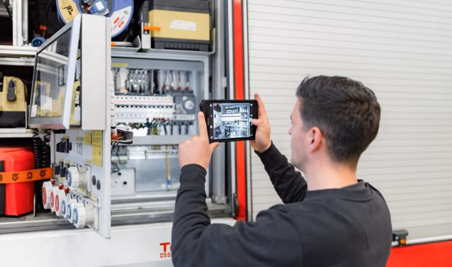Technicus inspecteert een elektrische schakelkast met een tablet tijdens een technische installatiecontrole.