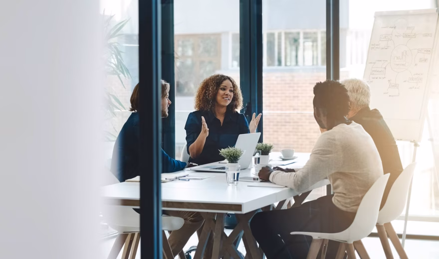 Réunion entre collaborateurs dans une salle de réunion aux parois vitrées lors d'un événement professionnel.