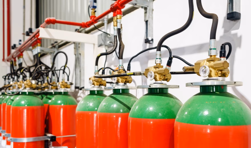 Gas fire suppression system with multiple fire suppression gas cylinders connected to piping for automatic fire suppression.