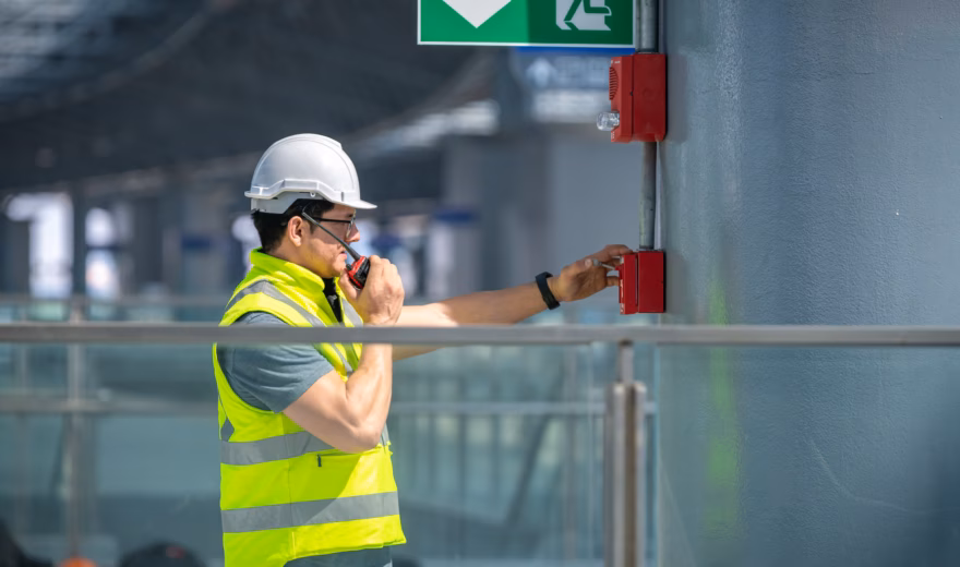 An employee tests a manual fire alarm as part of a fire alarm system in a building.