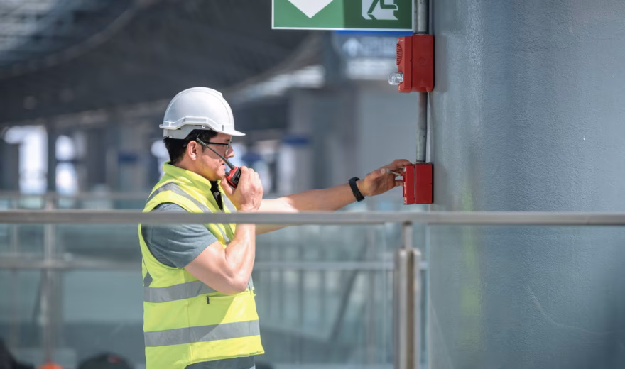 An employee tests a manual fire alarm as part of a fire alarm system in a building.