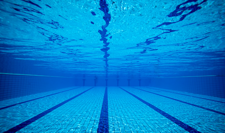 Ein leeres Schwimmbecken, in dem die Schwimmleinen auf dem Boden deutlich sichtbar sind.