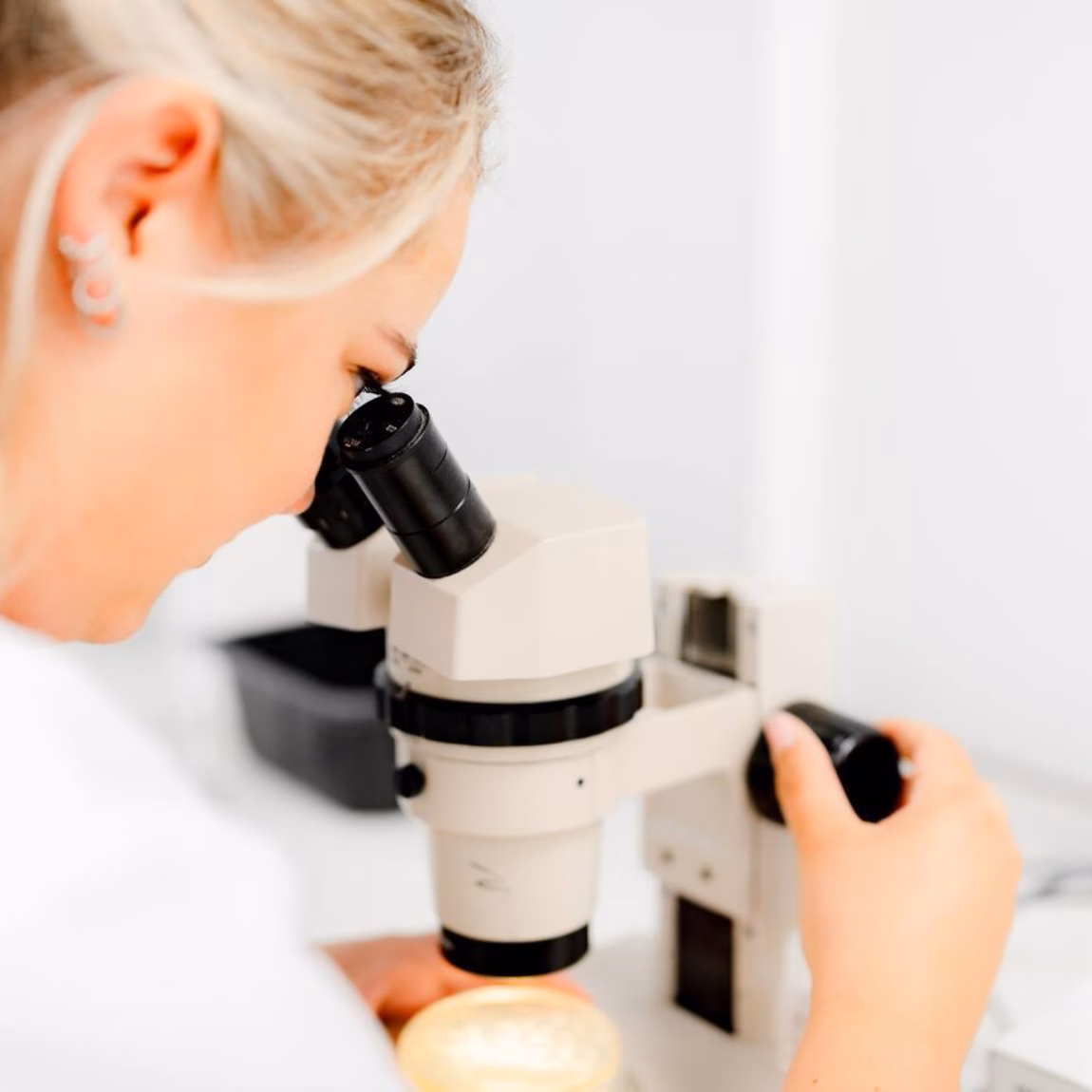 Une personne effectue des analyses en laboratoire à l'aide d'un microscope dans un environnement de recherche contrôlé.