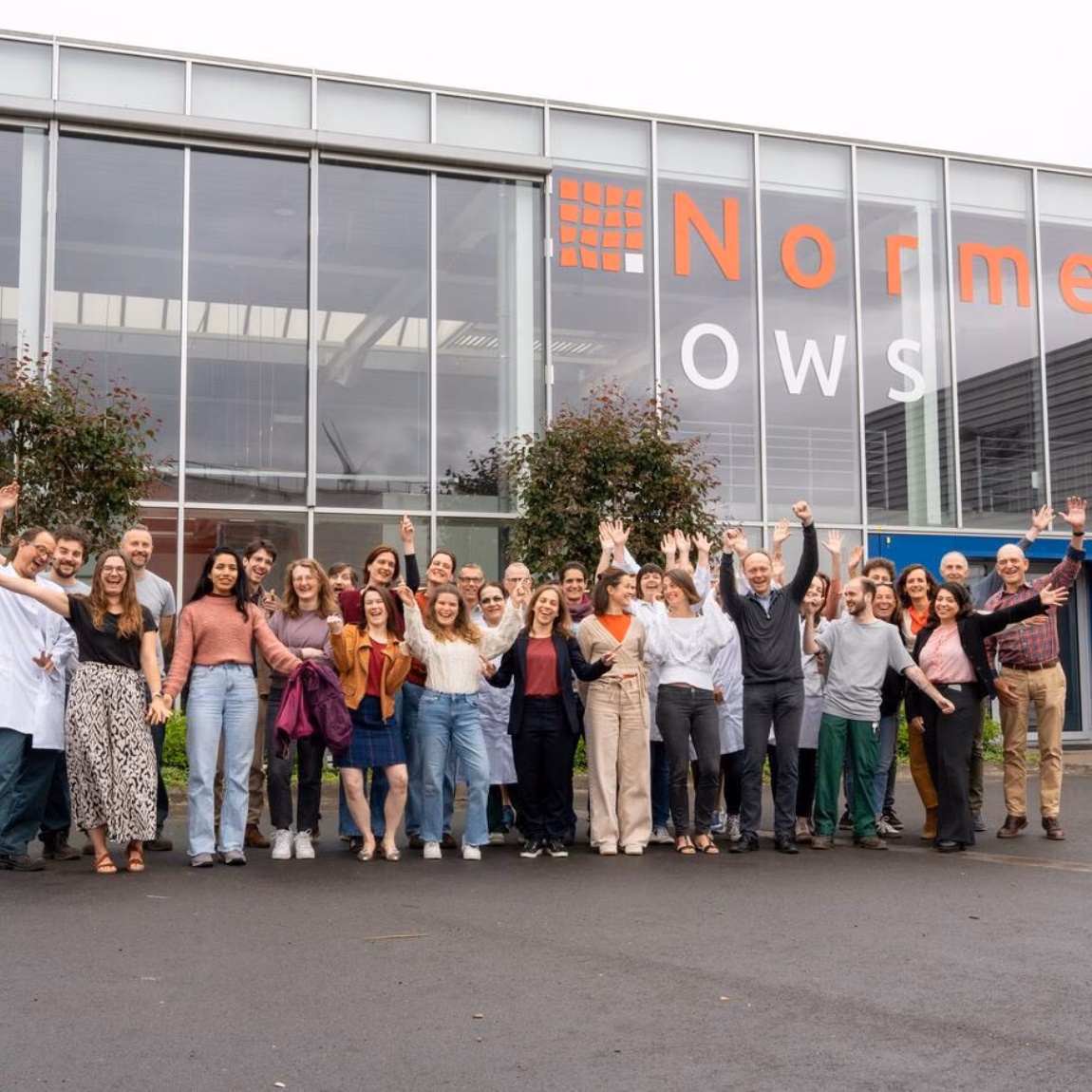 Groepsfoto van medewerkers voor een bedrijfspand van Normec OWS.