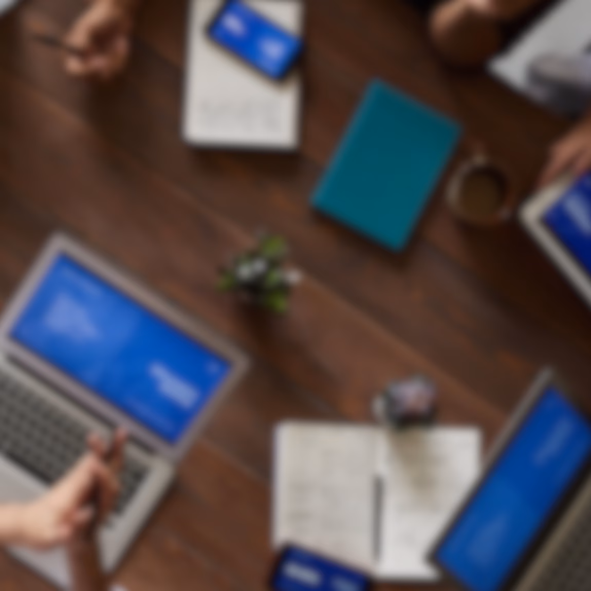 Top-Down-Ansicht von Fachkräften, die mit Laptops, Tablets, Notebooks und digitalen Präsentationen an einem Besprechungstisch zusammenarbeiten. Im Vordergrund stehen dabei strategische Planung, geschäftliche Zusammenarbeit, Projektmanagement, datengestützte Entscheidungsfindung und effektive Teamarbeit in einem modernen Unternehmensumfeld.