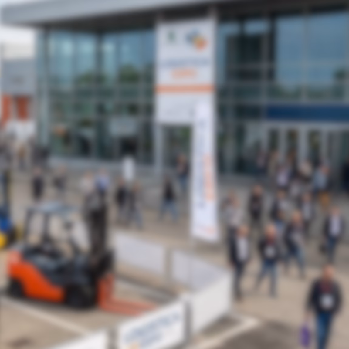 Besucher schlendern durch den Eingangsbereich einer großen Industriemesse mit Ausstellungshallen, Produktvorführungen und Gelegenheiten zum Networking, bei der Innovation, Geschäftsentwicklung, fachliche Zusammenarbeit sowie Fortschritte in den Bereichen Fertigung, Prüfung, Inspektion und Zertifizierungsdienstleistungen im Mittelpunkt stehen.