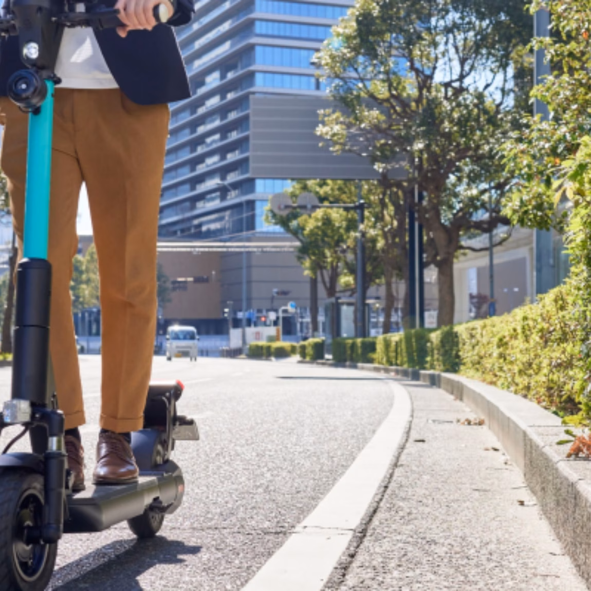 Ein E-Scooter-Fahrer fährt auf einem eigens dafür vorgesehenen städtischen Weg, umgeben von modernen Gebäuden und begrünten Anlagen, und verdeutlicht dabei die Bedeutung von Mikromobilitätslösungen, nachhaltigem Verkehr, Produktsicherheit, Einhaltung gesetzlicher Vorschriften und Innovation in städtischen Mobilitätssystemen.