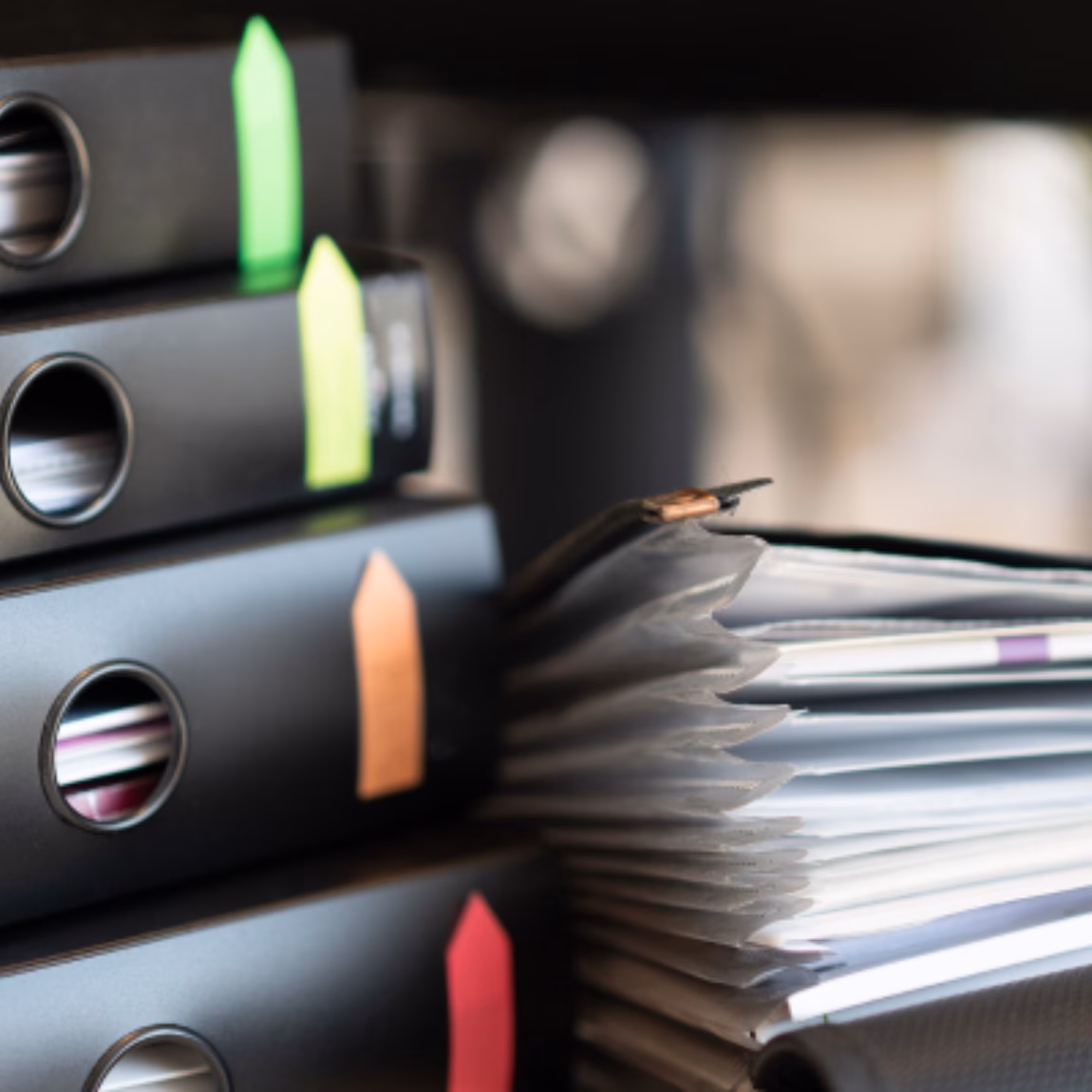 Übersichtlich angeordnete Ordner und Stapel von Geschäftsunterlagen auf einem Schreibtisch, die Dokumentenmanagement, Compliance-Aktenführung, Qualitätssicherung, behördliche Dokumentation und effiziente Informationsorganisation in einem professionellen Geschäftsumfeld verdeutlichen.
