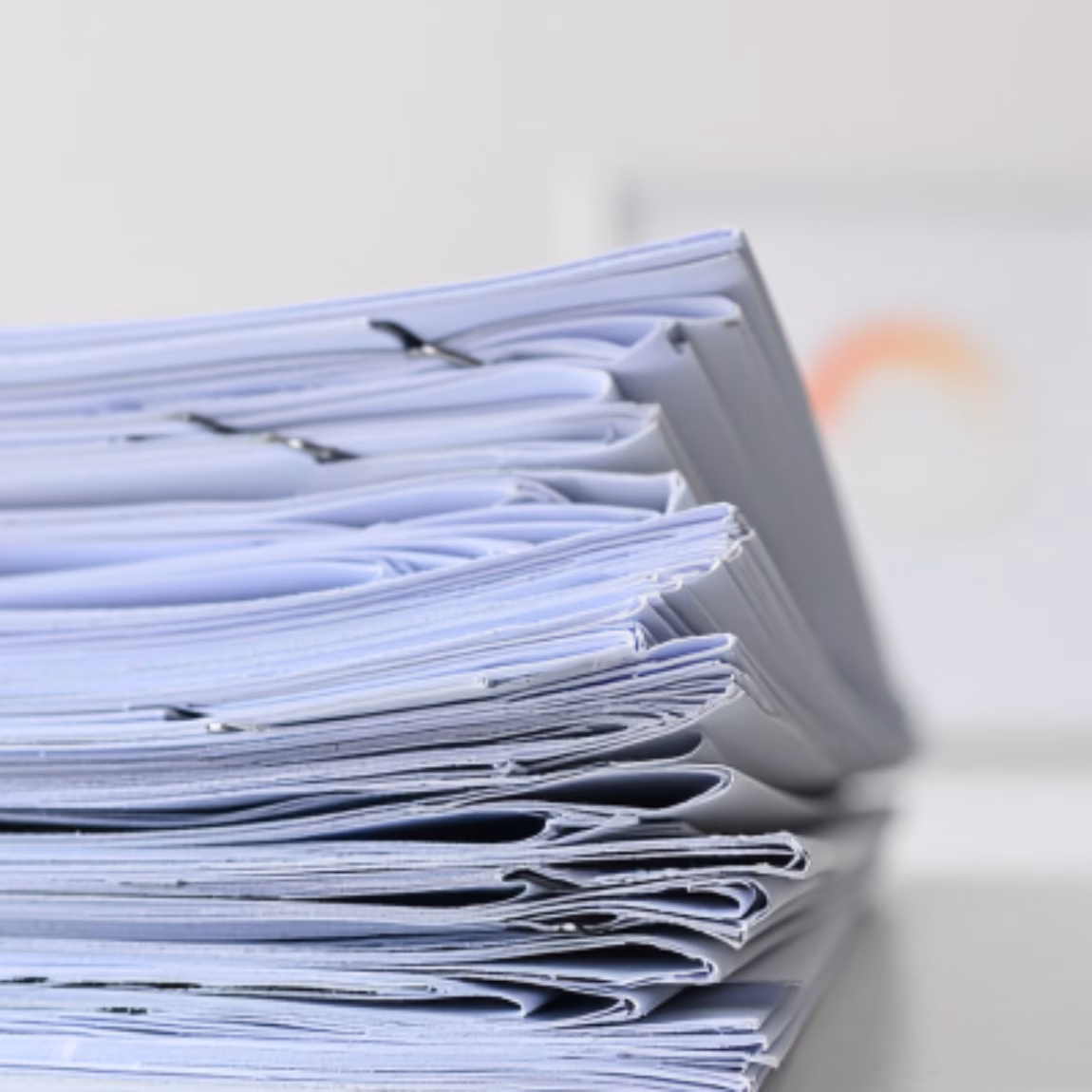 Ein Stapel ordentlich sortierter Papierdokumente auf einem Schreibtisch, der für Dokumentenmanagement, behördliche Unterlagen, Qualitätssicherung, Compliance-Prozesse, Aktenführung und administrative Unterstützung in einem professionellen Geschäftsumfeld steht.