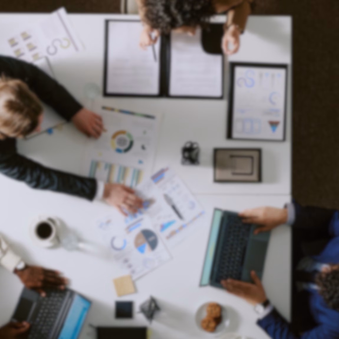 Fachleute sitzen gemeinsam am Besprechungstisch und prüfen Diagramme, Leistungsberichte und Geschäftsdaten, wobei der Schwerpunkt auf strategischer Planung, Datenanalyse, Projektmanagement und fundierter Entscheidungsfindung in einem modernen Unternehmensumfeld liegt.