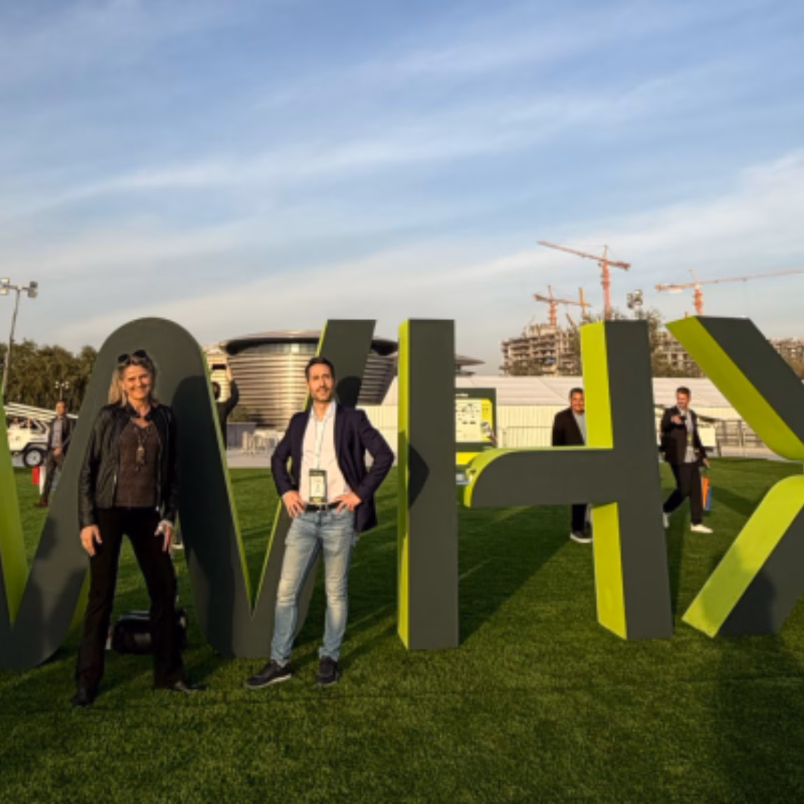 Besucher stehen neben einer großen VIVX-Ausstellungsinstallation auf einer Branchenveranstaltung im Freien, die Innovation, professionelles Networking, geschäftliche Zusammenarbeit und Wissensaustausch im Bereich Prüfung, Inspektion und Zertifizierung in den Vordergrund stellt.