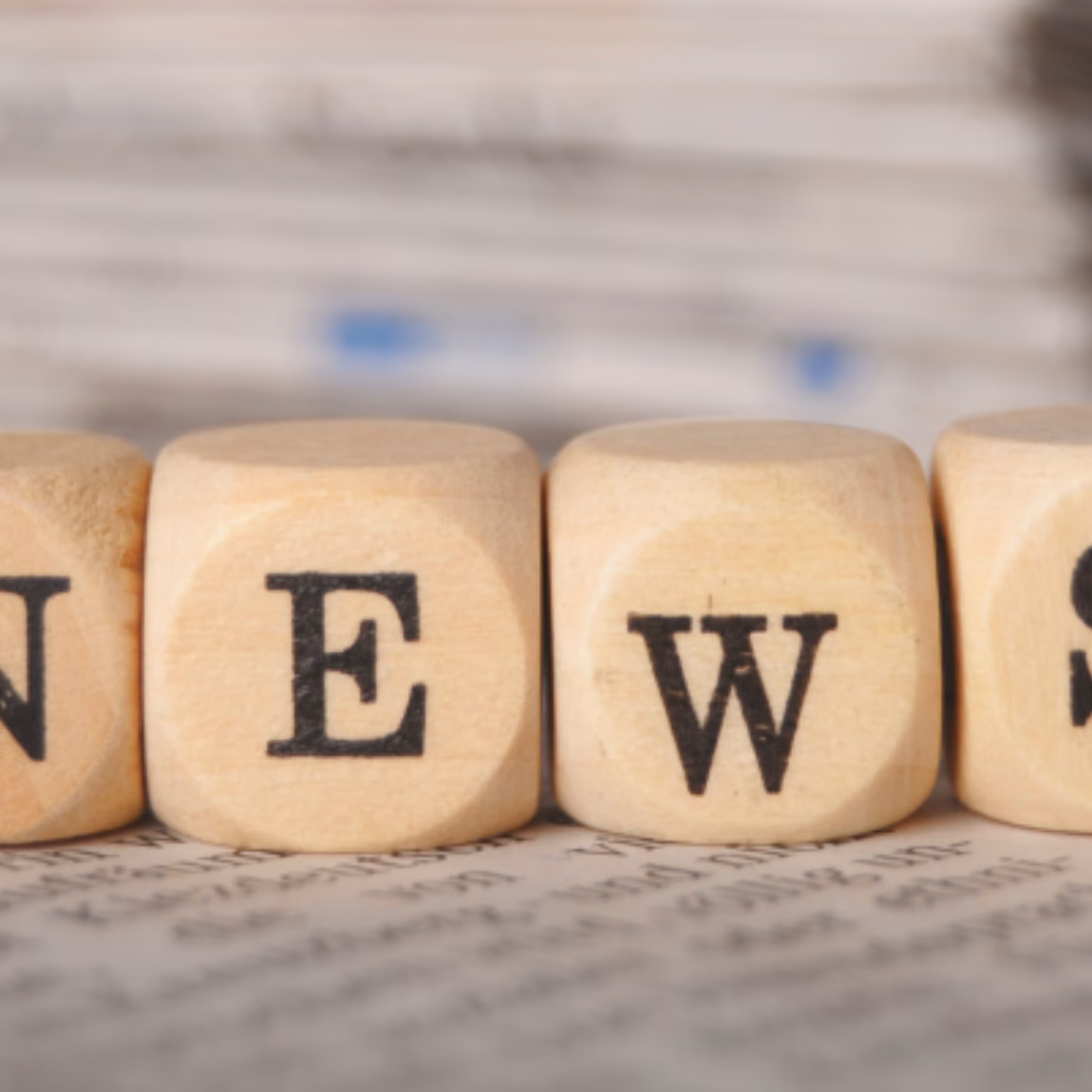 Holzbuchstaben, die vor einem Zeitungshintergrund das Wort „NEWS“ bilden, symbolisieren Unternehmensnachrichten, Branchenentwicklungen, Führungskräfte, Geschäftsanalysen und die neuesten Nachrichten über das Unternehmen.