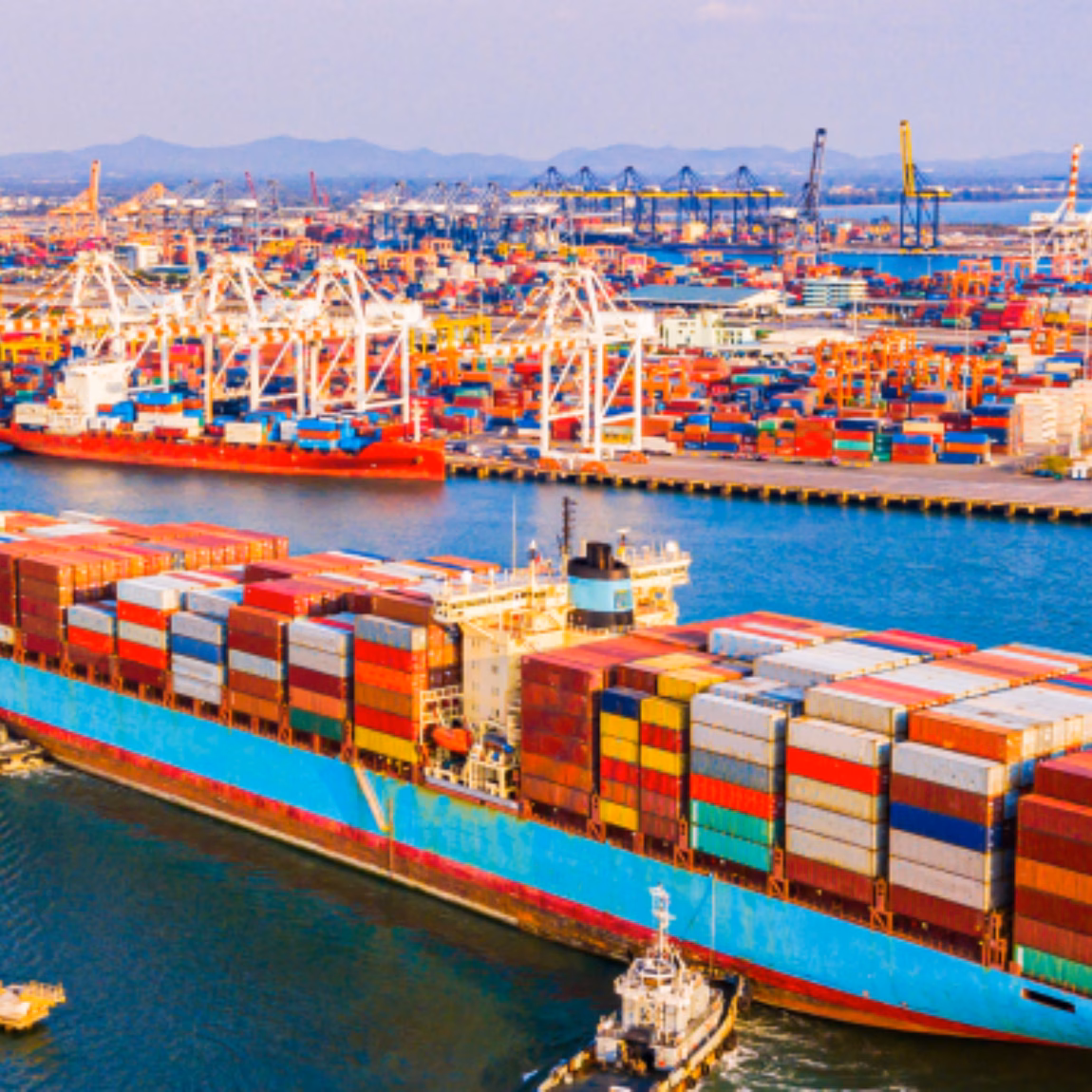 Ein großes Containerschiff, beladen mit bunten Containern, fährt durch einen geschäftigen Handelshafen und veranschaulicht damit den globalen Handel, die internationale Logistik, das Lieferkettenmanagement und die Seetransportdienstleistungen.