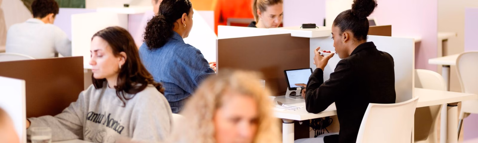 Medewerkers werken aan computers in een moderne kantooromgeving met open werkplekken en concentratieplekken.