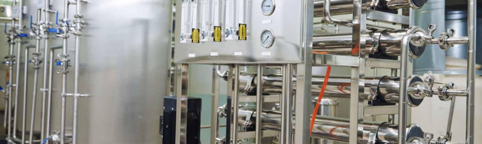 Stainless steel treatment and filtration systems installed in a modern industrial facility, consisting of interconnected tanks, piping, and control systems, used for quality-controlled production, cleaning, and manufacturing processes.