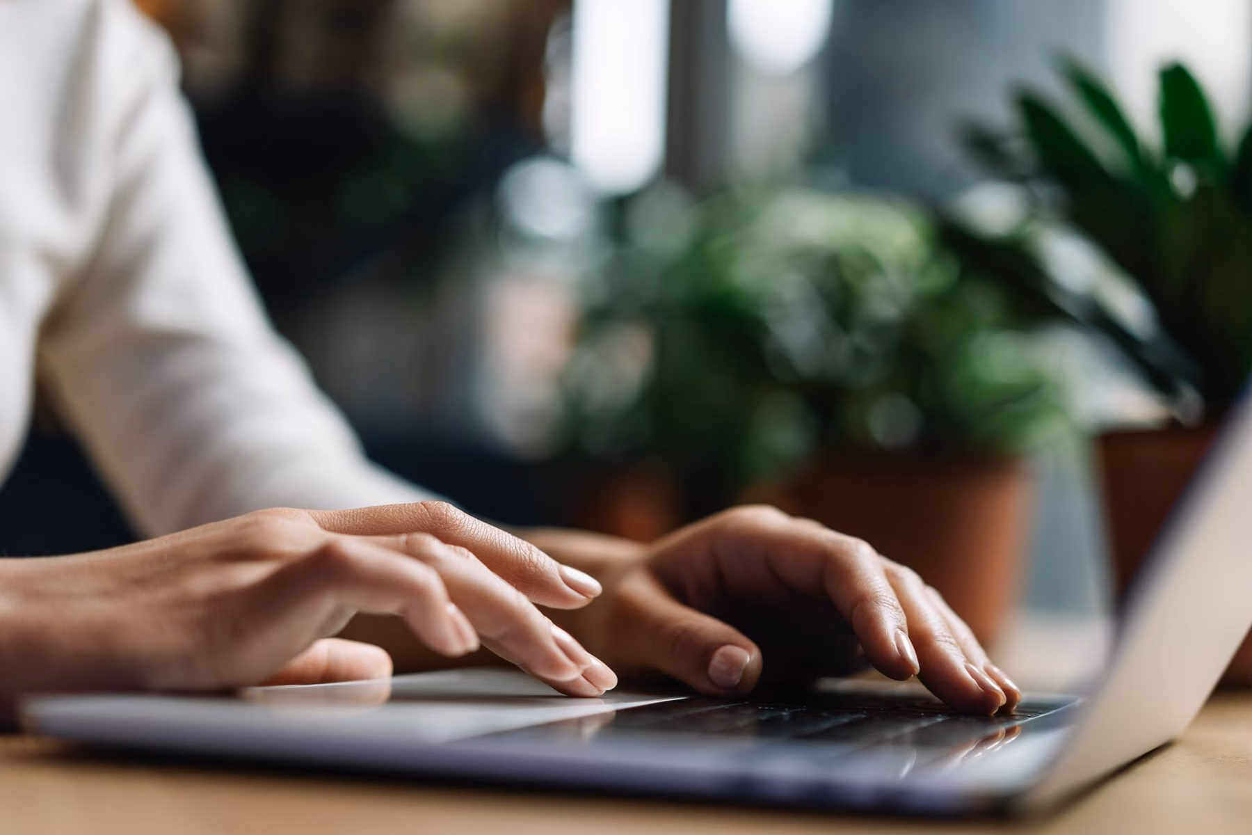 Hands working on a laptop while performing digital tasks in a modern workplace.