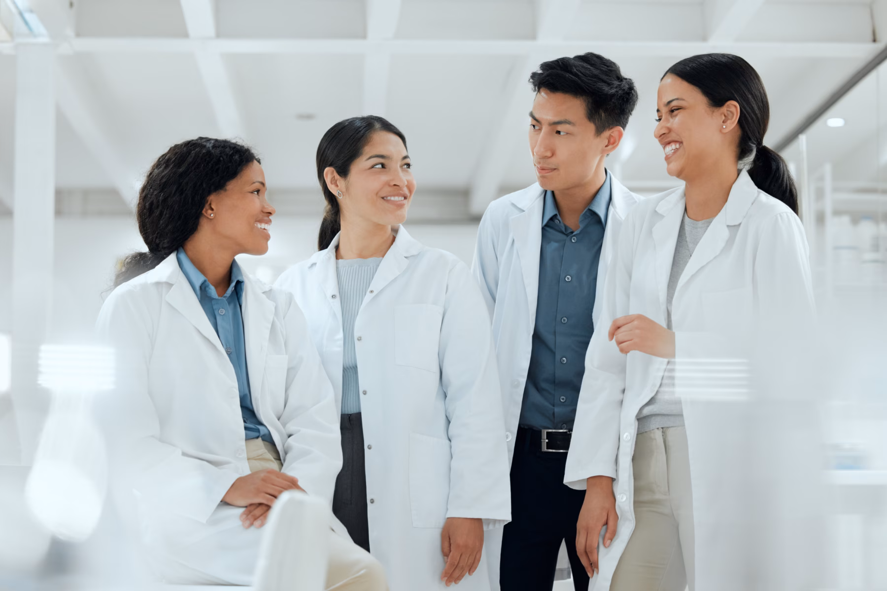 4 scientists in lab coats laughing in a laboratory