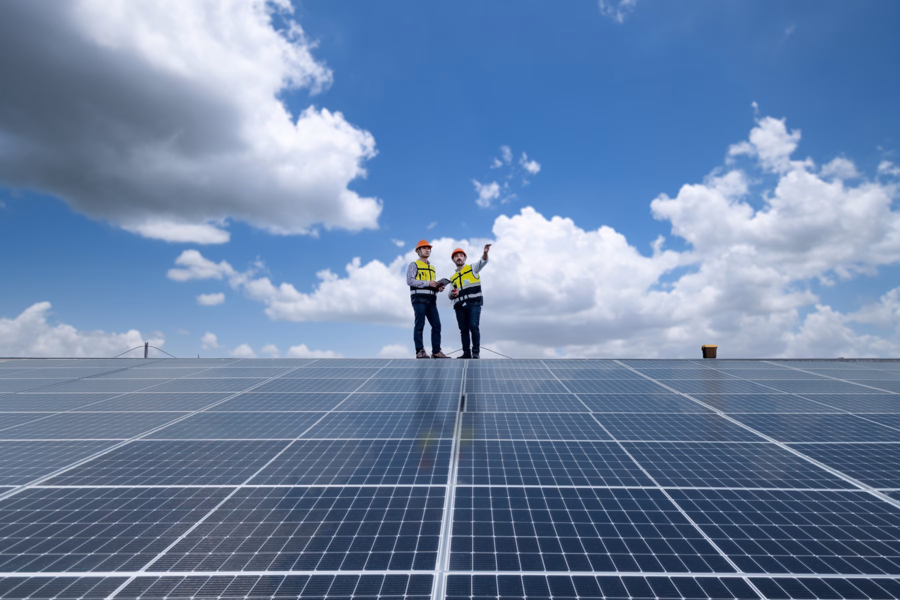 Mitarbeiter stehen auf einer Solaranlage, um das System zu inspizieren oder zu überprüfen.