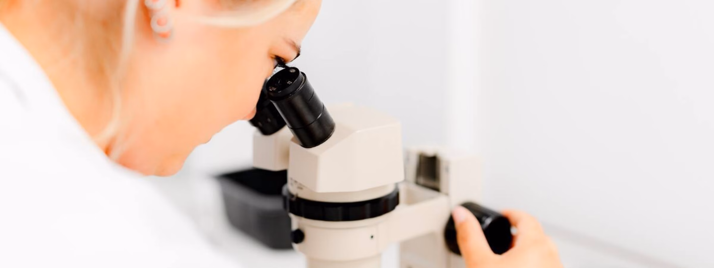 Une personne effectue des analyses en laboratoire à l'aide d'un microscope dans un environnement de recherche contrôlé.