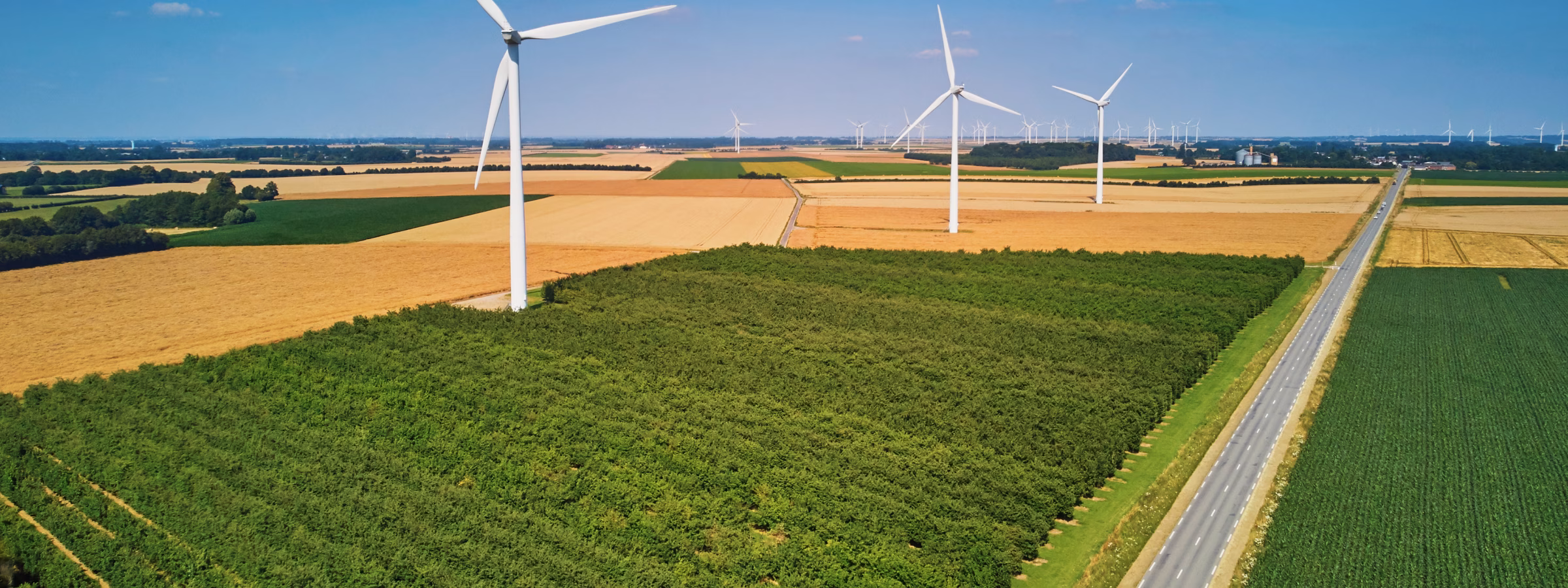 Wind turbines among farm fields in a rural landscape, as seen from the air.