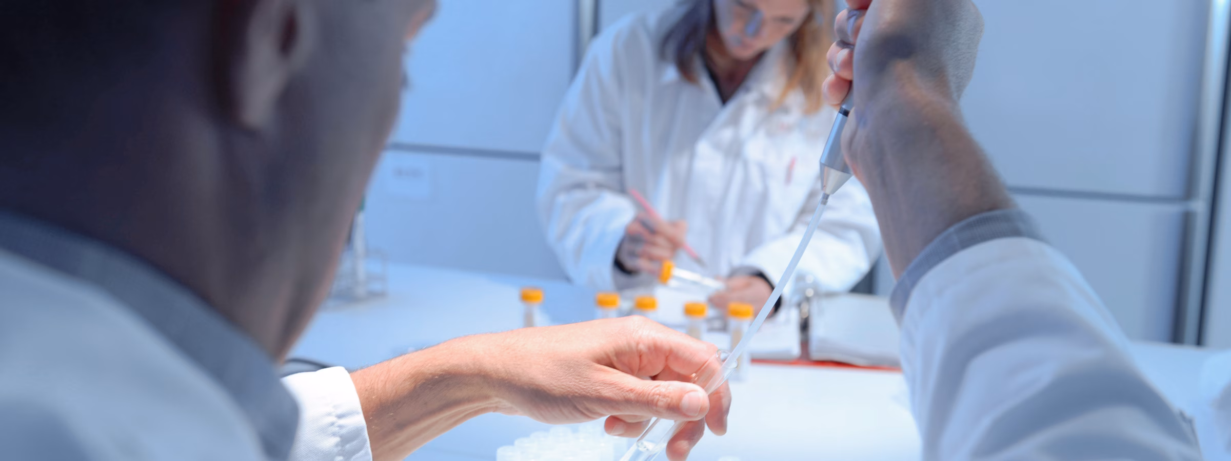 Laboratoriummedewerkers verwerken en analyseren vloeistofmonsters met pipetten in een modern onderzoekslaboratorium.