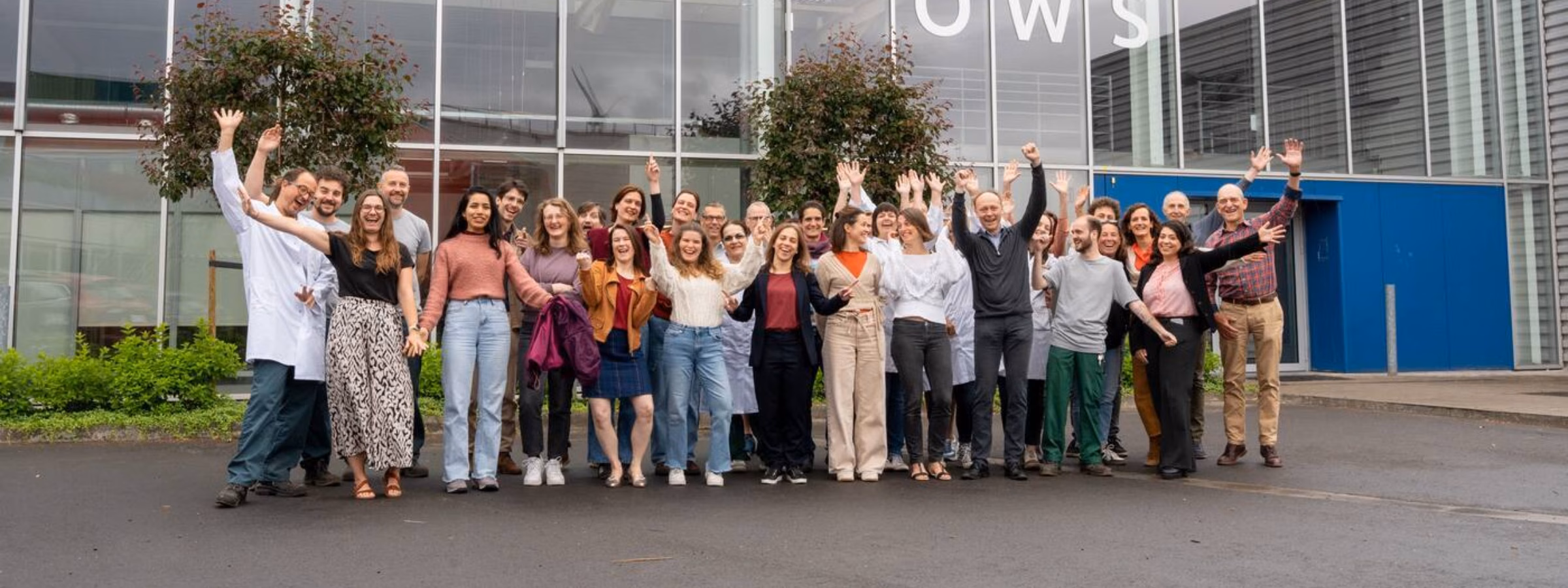Groepsfoto van medewerkers voor een bedrijfspand van Normec OWS.